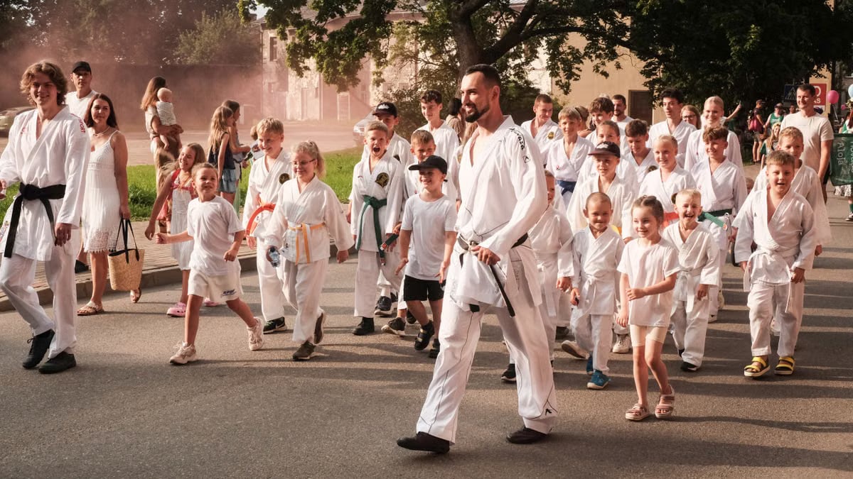 Group of people participating in a martial arts parade outdoors in Limbaži Municipality, Latvia.